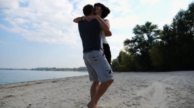 El ele tutuşup sahilde yürüyen bir çift. Adam kadını havaya uçurup kıyı şeridinde geri dönüyor. Mutlu çift yaz tatilinde deniz kıyısında birlikte eğleniyor. Aşk kavramı.