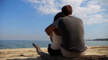 Sahilde tahta kütüğün üzerinde otururken romantik bir çift kucaklaşması. Denize ve manzaraya hayran olan mutlu bir çift. Sevgililer tatil köyünde birlikte vakit geçirirler. Tatil ya da tatil kavramı. Yavaş çekim