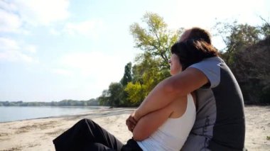 Sahilde tahta kütüğün üzerinde otururken romantik bir çift kucaklaşması. Denize ve manzaraya hayran olan mutlu bir çift. Sevgililer tatil köyünde birlikte vakit geçirirler. Tatil ya da tatil kavramı. Yavaş çekim