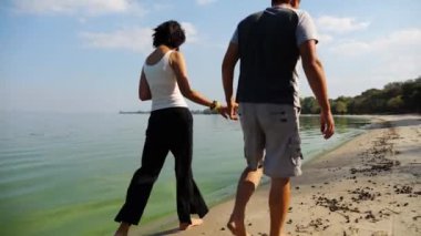 El ele tutuşup sahilde yürüyen bir çift. Güneşli bir günde deniz kıyısına giden mutlu bir çift. Sevgililer tatil köyünde birlikte vakit geçirirler. Tatil ya da tatil kavramı. Yavaş çekim