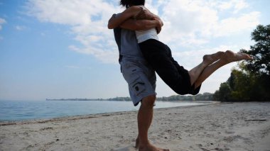 El ele tutuşup sahilde yürüyen bir çift. Adam kadını havaya uçurup kıyı şeridinde geri dönüyor. Mutlu çift yaz tatilinde deniz kıyısında birlikte eğleniyor. Aşk kavramı.