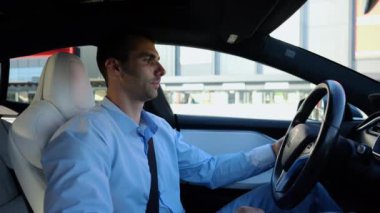 Kentsel yolda kendi kendini kullanan bir erkek işadamı deneyimi. Şehirdeki otomatik pilotla elektrikli otomobilde dinlenen kendine güvenen bir iş adamı. Yavaş çekim