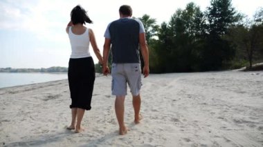 El ele tutuşup sahilde yürüyen bir çift. Güneşli bir günde deniz kıyısına giden mutlu bir çift. Sevgililer tatil köyünde birlikte vakit geçirirler. Tatil ya da tatil kavramı. Yavaş çekim