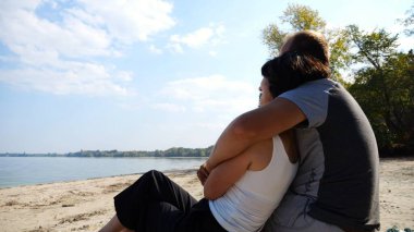 Sahilde tahta kütüğün üzerinde otururken romantik bir çift kucaklaşması. Denize ve manzaraya hayran olan mutlu bir çift. Sevgililer tatil köyünde birlikte vakit geçirirler. Tatil ya da tatil kavramı. Yavaş çekim