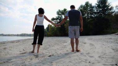 El ele tutuşup sahilde yürüyen bir çift. Adam kadını havaya uçurup kıyı şeridinde geri dönüyor. Mutlu çift yaz tatilinde deniz kıyısında birlikte eğleniyor. Aşk kavramı.