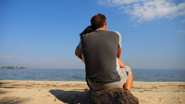 Sahilde tahta kütüğün üzerinde otururken romantik bir çift kucaklaşması. Denize ve manzaraya hayran olan mutlu bir çift. Sevgililer tatil köyünde birlikte vakit geçirirler. Tatil ya da tatil kavramı. Yavaş çekim