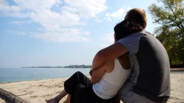 Sahilde tahta kütüğün üzerinde otururken romantik bir çift kucaklaşması. Denize ve manzaraya hayran olan mutlu bir çift. Sevgililer tatil köyünde birlikte vakit geçirirler. Tatil ya da tatil kavramı. Yavaş çekim