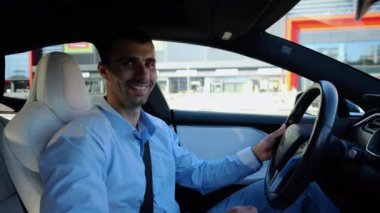 Kentsel yolda kendi kendini kullanan bir erkek işadamı deneyimi. Şehirdeki otomatik pilotla elektrikli otomobilde dinlenen kendine güvenen bir iş adamı. Yavaş çekim