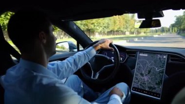 Başarılı bir iş adamı şehirde elektrikli araçla dolaşıyor. Kentsel yolda modern elektrikli araba kullanan bir erkek girişimci. Güneşli bir günde otomotiv işi yapan bir iş adamı. İşe gidip gelen genç adam..