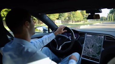 Başarılı bir iş adamı şehirde elektrikli araçla dolaşıyor. Kentsel yolda modern elektrikli araba kullanan bir erkek girişimci. Güneşli bir günde otomotiv işi yapan bir iş adamı. İşe gidip gelen genç adam..