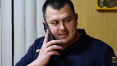 Erkek itfaiyeci şefi, itfaiye istasyonunda astıyla ciddi bir telefon görüşmesi yapıyor. İtfaiyeci itfaiyede cep telefonuyla konuşuyor. Kahramanlık kavramı..