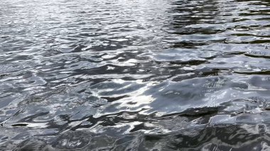 Yazın güneşle aydınlatılan göletin manzara yüzeyi. Güneşli bir günde deniz manzarası ve küçük dalgalar. Güzel yaz doğa manzarası. Huzur sahnesi kavramı. Yavaş çekim