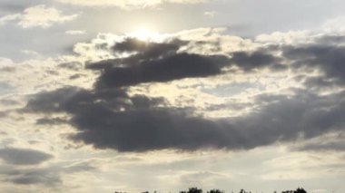 Gün batımında kümülüs bulutunu aşan güneş ışığı. Yaz günü gökyüzünde gri bulutların ardında güneş batıyor. Güzel bir doğa geçmişi var. Yavaşla.