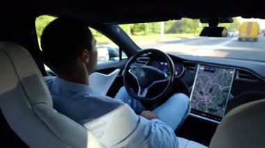 Kentsel yolda kendi kendini kullanan bir erkek işadamı deneyimi. Şehirdeki otomatik pilotla elektrikli otomobilde dinlenen kendine güvenen bir iş adamı. Yavaş çekim