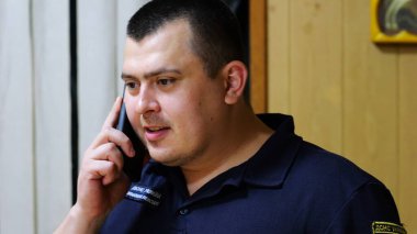 Erkek itfaiyeci şefi, itfaiye istasyonunda astıyla ciddi bir telefon görüşmesi yapıyor. İtfaiyeci itfaiyede cep telefonuyla konuşuyor. Kahramanlık kavramı..