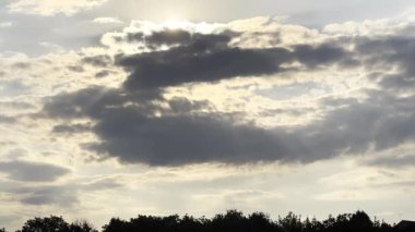 Gün batımında kümülüs bulutunu aşan güneş ışığı. Yaz günü gökyüzünde gri bulutların ardında güneş batıyor. Güzel bir doğa geçmişi var. Yavaşla.