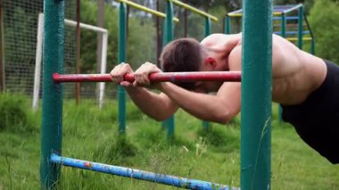 Spor malzemelerinde trisepsler üzerinde egzersiz yapan genç kaslı bir atlet. Spor sahasında spor yapan erkek üstsüz sporcu. Doğada güçlü bir sporcu eğitimi. Sağlıklı yaşam tarzı kavramı.
