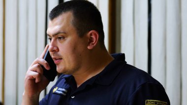 Erkek itfaiyeci şefi, itfaiye istasyonunda astıyla ciddi bir telefon görüşmesi yapıyor. İtfaiyeci itfaiyede cep telefonuyla konuşuyor. Kahramanlık kavramı..