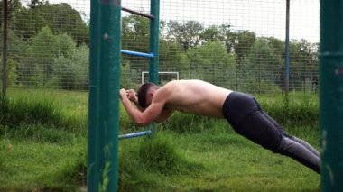 Spor malzemelerinde trisepsler üzerinde egzersiz yapan genç kaslı bir atlet. Spor alanında spor yapan erkek üstsüz bir sporcu. Doğada güçlü bir sporcu eğitimi. Sağlıklı yaşam tarzı kavramı.