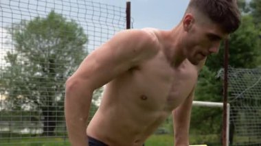 Erkek üstsüz sporcu doğada paralel barlarda şınav çekiyor. Spor alanında egzersiz yapan güçlü bir sporcu. Genç sporcu dışarıda sıkı çalışıyor. Aktif spor yaşam tarzı kavramı. Yavaş