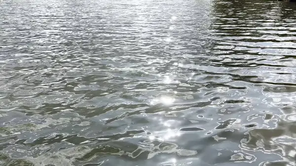Yazın güneşle aydınlatılan göletin manzara yüzeyi. Güneşli bir günde deniz manzarası ve küçük dalgalar. Güzel yaz doğa manzarası. Huzur sahnesi kavramı. Yavaş çekim