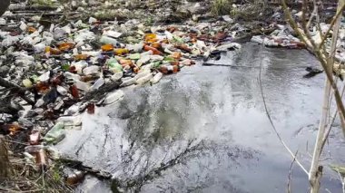 Kirli nehir birçok plastik şişeyle kirlidir. Pek çok çöp doğadaki açık ve serbestçe ulaşılabilir yerlere atılır. Küresel çevre kirliliği sorunu. Ekolojik felaket kavramı.