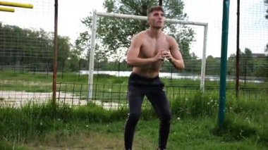 Spor sahasında çömelme hareketleri yapan erkek üstsüz atlet. Yaz doğasında çalışan genç bir sporcu. Güçlü sporcu dışarıda egzersiz yapıyor. Aktif ve sportif yaşam tarzı kavramı. Yavaş çekim