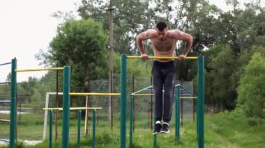 Cesur üstsüz sporcu doğada yatay çıtada şınav çekiyor. Güçlü ve kaslı adam spor alanında antrenman yapıyor. Genç atletik adam dışarıda egzersiz yapıyor. Aktif ve sağlıklı yaşam tarzı kavramı.
