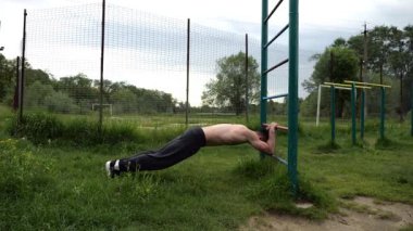 Spor malzemelerinde trisepsler üzerinde egzersiz yapan genç kaslı bir atlet. Spor alanında spor yapan erkek üstsüz bir sporcu. Doğada güçlü bir sporcu eğitimi. Sağlıklı yaşam tarzı kavramı.