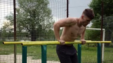 Erkek üstsüz sporcu doğada paralel barlarda şınav çekiyor. Spor alanında egzersiz yapan güçlü bir sporcu. Genç sporcu dışarıda sıkı çalışıyor. Aktif spor yaşam tarzı kavramı. Yavaş çekim