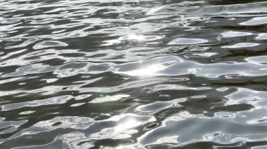 Yazın güneşle aydınlatılan göletin manzara yüzeyi. Güneşli bir günde deniz manzarası ve küçük dalgalar. Güzel yaz doğa manzarası. Huzur sahnesi kavramı. Yavaş çekim