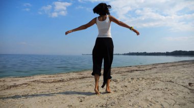Güneşli bir günde sahil kenarında kumsalda yürüyen güzel bir bayan. Mutlu yetişkin kadın kıyı şeridine doğru dönüyor. Kaygısız kadın deniz kenarında dinleniyor. Yaz tatili veya tatil kavramı