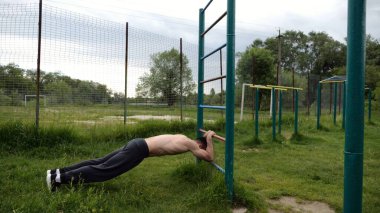 Spor malzemelerinde trisepsler üzerinde egzersiz yapan genç kaslı bir atlet. Spor alanında spor yapan erkek üstsüz bir sporcu. Doğada güçlü bir sporcu eğitimi. Sağlıklı yaşam tarzı kavramı.