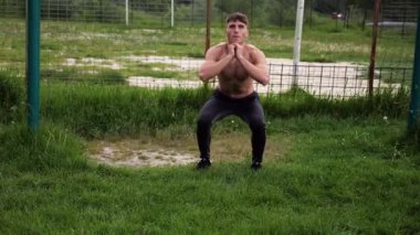 Spor sahasında çömelme hareketleri yapan erkek üstsüz atlet. Yaz doğasında çalışan genç bir sporcu. Güçlü sporcu dışarıda egzersiz yapıyor. Aktif ve sportif yaşam tarzı kavramı. Yavaş çekim