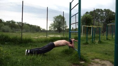 Spor malzemelerinde trisepsler üzerinde egzersiz yapan genç kaslı bir atlet. Spor alanında spor yapan erkek üstsüz bir sporcu. Doğada güçlü bir sporcu eğitimi. Sağlıklı yaşam tarzı kavramı.