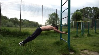 Spor malzemelerinde trisepsler üzerinde egzersiz yapan genç kaslı bir atlet. Spor alanında spor yapan erkek üstsüz bir sporcu. Doğada güçlü bir sporcu eğitimi. Sağlıklı yaşam tarzı kavramı.