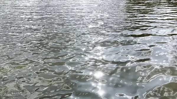 Yazın güneşle aydınlatılan göletin manzara yüzeyi. Güneşli bir günde deniz manzarası ve küçük dalgalar. Güzel yaz doğa manzarası. Huzur sahnesi kavramı. Yavaş çekim