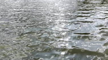 Yazın güneşle aydınlatılan göletin manzara yüzeyi. Güneşli bir günde deniz manzarası ve küçük dalgalar. Güzel yaz doğa manzarası. Huzur sahnesi kavramı. Yavaş çekim