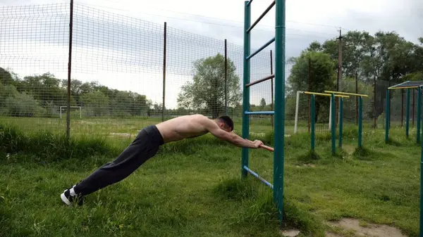 Spor malzemelerinde trisepsler üzerinde egzersiz yapan genç kaslı bir atlet. Spor alanında spor yapan erkek üstsüz bir sporcu. Doğada güçlü bir sporcu eğitimi. Sağlıklı yaşam tarzı kavramı.