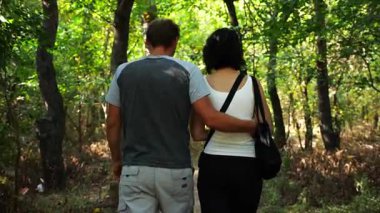 Mutlu çift yaz ormanında yolda yürüyor. Vahşi ormanlık alanda romantik bir çift geziyor. Sevgililer doğada birlikte vakit geçirirler. Aşk ve mutluluk kavramı. Yavaş çekim