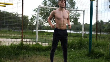 Spor sahasında çömelme hareketleri yapan erkek üstsüz atlet. Yaz doğasında çalışan genç bir sporcu. Güçlü sporcu dışarıda egzersiz yapıyor. Aktif ve sportif yaşam tarzı kavramı. Yavaş çekim