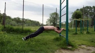 Spor malzemelerinde trisepsler üzerinde egzersiz yapan genç kaslı bir atlet. Spor sahasında spor yapan erkek üstsüz sporcu. Doğada güçlü bir sporcu eğitimi. Sağlıklı yaşam tarzı kavramı.