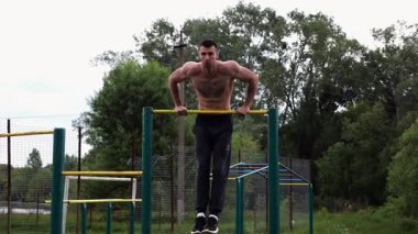 Cesur üstsüz sporcu doğada yatay çıtada şınav çekiyor. Güçlü ve kaslı adam spor alanında antrenman yapıyor. Genç atletik adam dışarıda egzersiz yapıyor. Aktif ve sağlıklı yaşam tarzı kavramı.