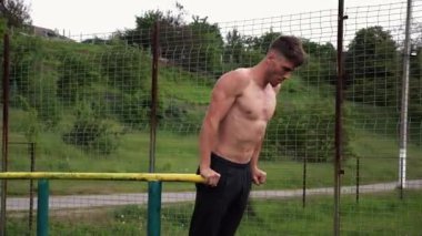 Genç sporcu doğada paralel barlarda şınav çekiyor. Spor alanında egzersiz yapan güçlü bir sporcu. Erkek üstsüz sporcu dışarıda sıkı çalışıyor. Aktif spor yaşam tarzı kavramı. Yavaş çekim