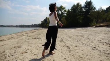 Güneşli bir günde sahilde koşan mutlu yetişkin kadın. Arka planda sakin dalgalarla deniz kıyısında koşan güzel bir bayan. Yaz tatili ya da tatil kavramı. Yavaş çekim