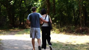 Mutlu çift yaz ormanında yolda yürüyor. Vahşi ormanlık alanda romantik bir çift geziyor. Sevgililer doğada birlikte vakit geçirirler. Aşk ve mutluluk kavramı. Yavaş çekim