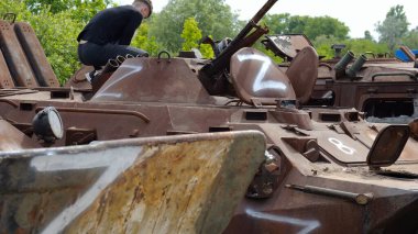 Rus ordusunun yok edilmiş askeri teçhizatına bakan genç adam. Ukrayna bölgesinde paslı ve yanmış zırhlı araçların sergilenmesi. Ukrayna ve Rusya arasındaki savaş. Yavaş çekim