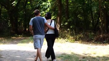 Mutlu çift yaz ormanında yolda yürüyor. Vahşi ormanlık alanda romantik bir çift geziyor. Sevgililer doğada birlikte vakit geçirirler. Aşk ve mutluluk kavramı. Yavaş çekim
