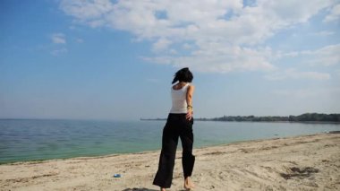 Güneşli bir günde sahilde koşan mutlu yetişkin kadın. Arka planda sakin dalgalarla deniz kıyısında koşan güzel bir bayan. Yaz tatili ya da tatil kavramı. Yavaş çekim