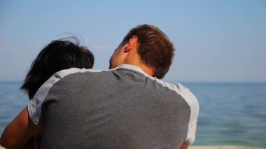 Kumsalda tahta kütüğün üzerinde otururken mutlu çift kucaklaşması. Romantik bir adam sahil kenarında sevgilisini öpüyor. Kaygısız aşıklar tatil köyünde birlikte vakit geçiriyorlar. Yaz tatili veya tatil kavramı.